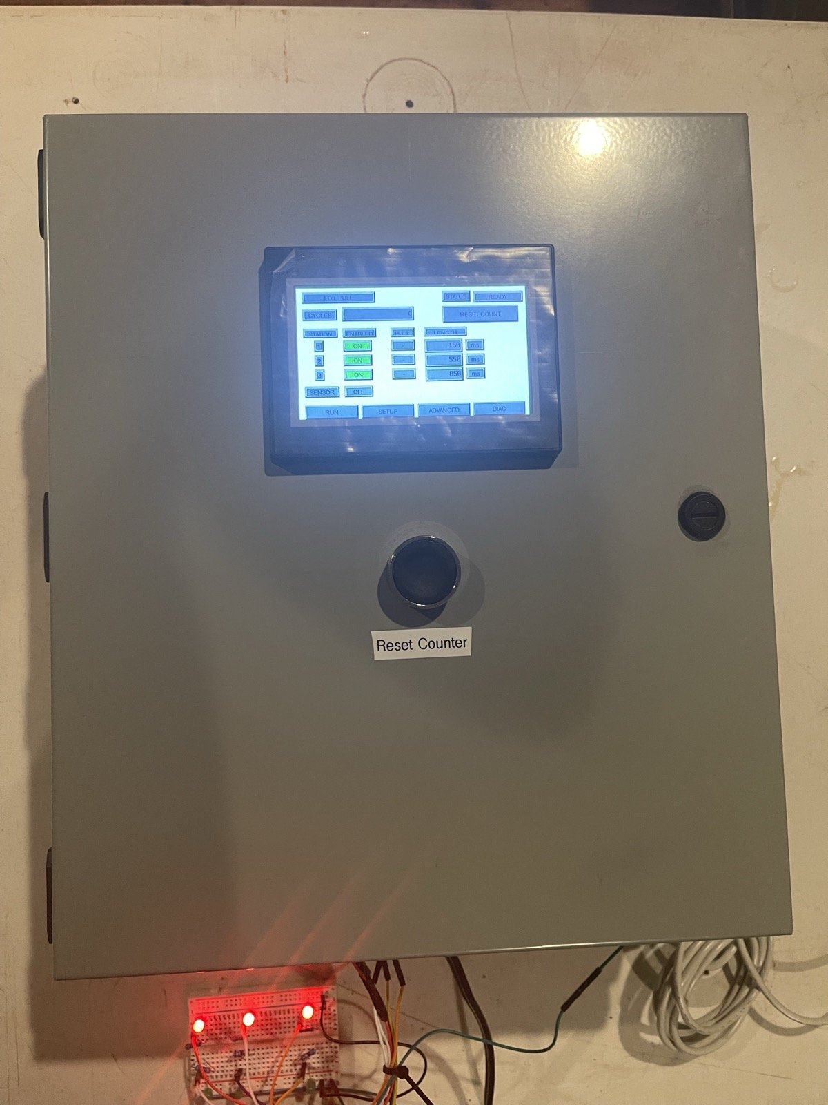 Finished panel door with touchscreen and Reset Counter pushbutton, LED test rig below